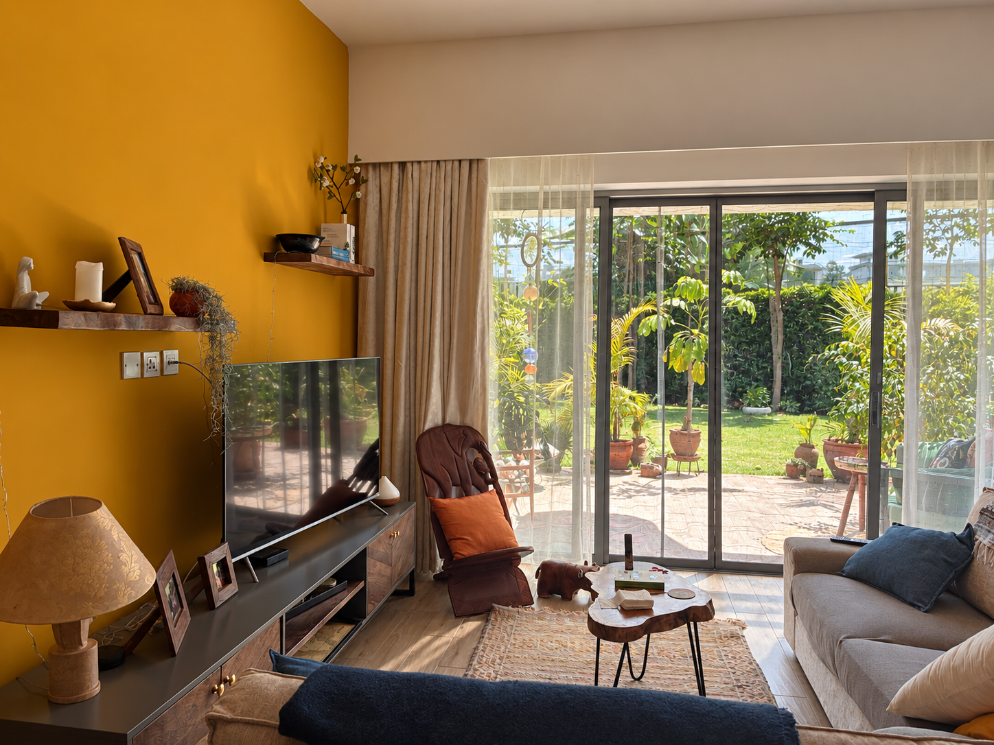 Private residence living room in Nairobi with an ochre wall opening onto a planted garden